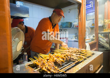 Peking, China - Koch Kochen Fleisch auf Stöcken in der Donghuamen Nachtmarkt Snack, eine große outdoor-Markt, das ist eine Attraktion Stockfoto