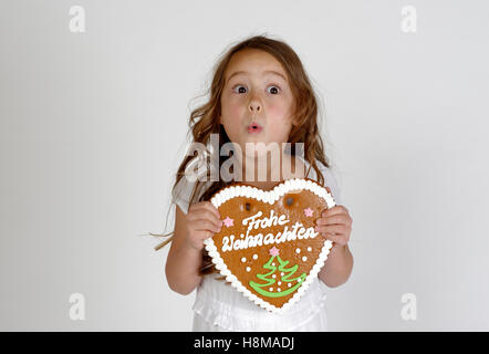 Erstaunt kleines Kind, Mädchen mit Lebkuchen Herz, Frohe Weihnachten, Weihnachtszeit, Deutschland Stockfoto