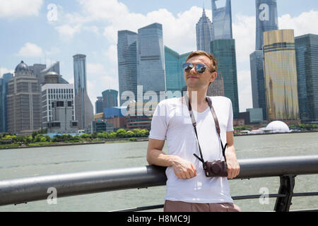 Nachdenklicher Mann stützte sich auf Geländer gegen Shanghai World Financial Center Stockfoto