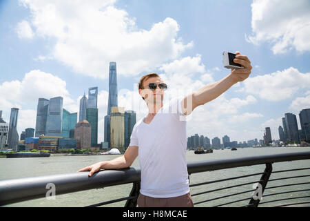 Mann mit Sonnenbrille während der Einnahme von Selfie gegen Skyline von Pudong Stockfoto