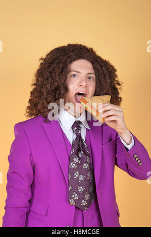 Kaukasischen Mann mit Afro violett Anzug Sandwich zu essen Stockfoto