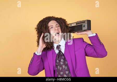 Kaukasischen Mann mit Afro lila Anzug anhören von Musik Stockfoto