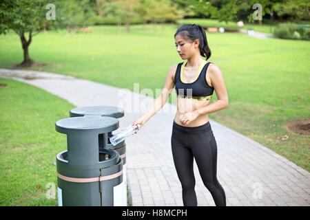 Schöne asiatische Frau recycling im Park nach ihrem Lauf Stockfoto