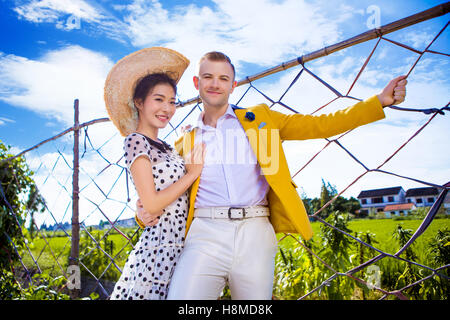 Porträt des glücklichen Paares tatenlos Zaun am Feld gegen Himmel Stockfoto