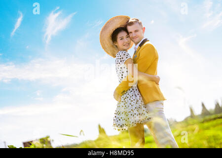 Seite Ansicht Porträt des romantischen Paares auf Feld gegen Himmel umarmen Stockfoto