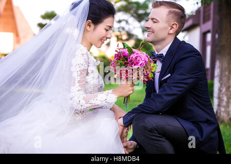 Glückliche Bräutigam Blick auf schöne Braut hält Blumenstrauss im freien Stockfoto