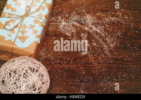 Weihnachts-Geschenk liegt auf einem Holztisch, verpackt in Kraftpapier mit einer blaue Schneeflocke Stockfoto