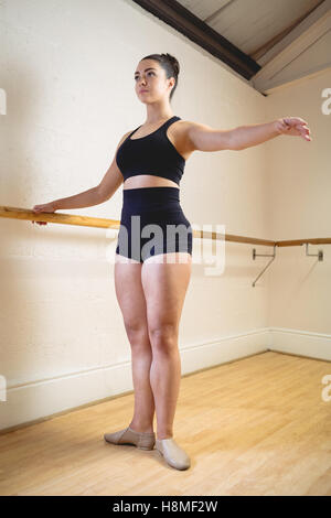 Ballerina, die Dehnung auf eine Barre beim Praktizierenden Ballett-Tanz Stockfoto