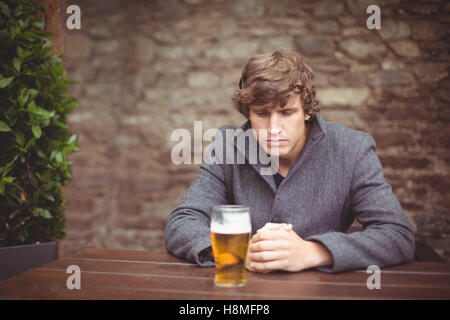 Mann sitzt in der Bar mit Glas Bier auf Tisch Stockfoto