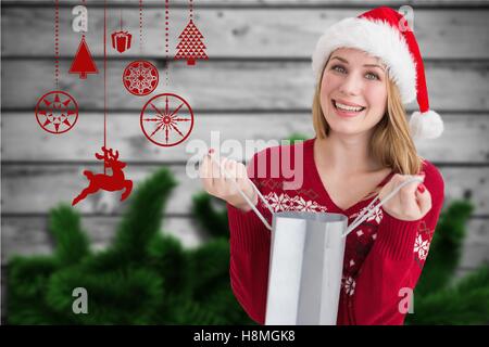 Schöne Frau in Weihnachtsmütze hält eine Einkaufstasche Stockfoto