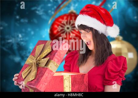 Überrascht Frau in Nikolausmütze Blick auf Weihnachtsgeschenke Stockfoto