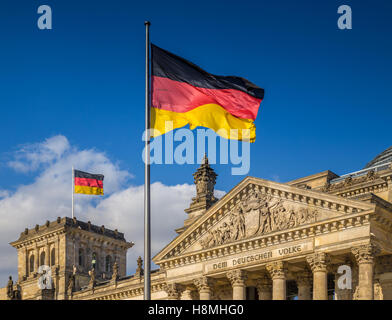 Deutsche Flaggen wehten im Wind am berühmten Reichstagsgebäude, Sitz des Deutschen Bundestages, an einem sonnigen Tag in Berlin, Deutschland Stockfoto