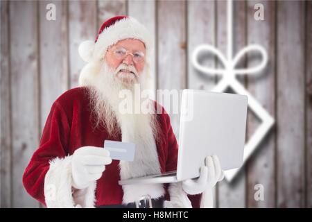 Santa Claus macht Online-shopping mit Kreditkarte auf laptop Stockfoto