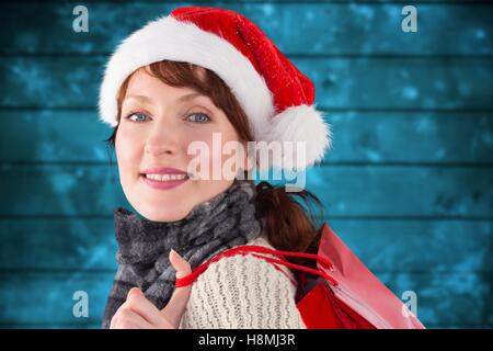 Frau in Weihnachtsmütze hält eine Einkaufstasche Stockfoto