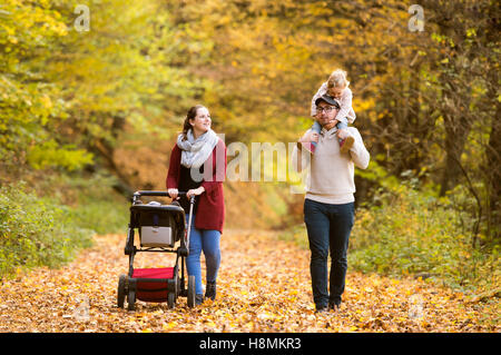 Schöne junge Familie auf einem Spaziergang im Herbstwald. Stockfoto