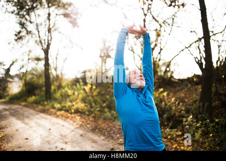 Senior Läufer tun stretching im sonnigen Herbst Natur. Stockfoto