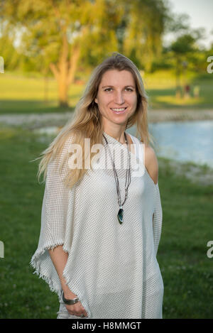 Attraktive blonde junge Frau in einem Park mit unscharfen Hintergrund Stockfoto