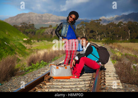 afrikanischer Mann und ein Mädchen warten auf Zug auf den Gleisen Stockfoto