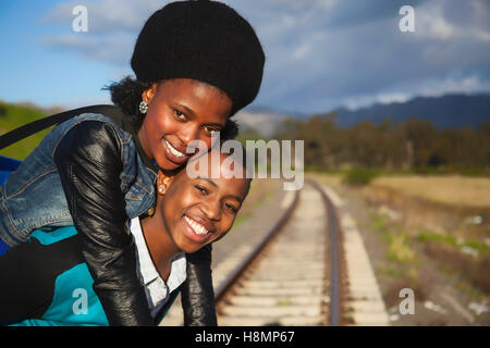 afrikanischer Mann und ein Mädchen warten auf Zug auf den Gleisen Stockfoto