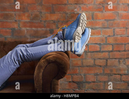 Halben Körper einer Frau posiert ihre Jeans und Stiefel auf dem sofa Stockfoto