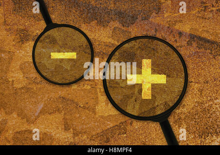 Mathematische Zeichen für Addition und Subtraktion unter einer Lupe Stockfoto