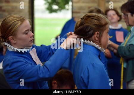 Chorknaben an Soutane passend und Proben für Abendandacht. Ein Mädchen Chorknabe bindet ein anderes Mädchen Haare. Stockfoto