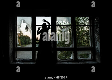 Halloween Hexe Silhouette stehen auf der Fensterbank des Fensterrahmens. Stockfoto