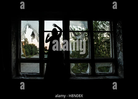 Halloween Hexe Silhouette stehen auf der Fensterbank des Fensterrahmens. Stockfoto