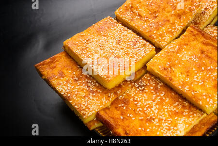 Stück Käsekuchen mit Sesam auf schwarzem Hintergrund Stockfoto