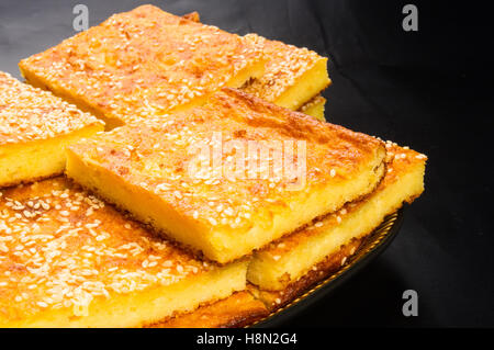 Stück Käsekuchen mit Sesam auf schwarzem Hintergrund Stockfoto