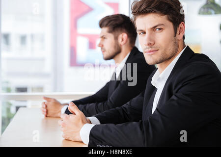 Zwei schwere junge Geschäftsleute im Anzug im Büro sitzen Stockfoto