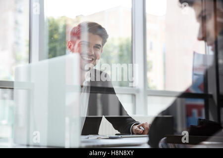 Zwei fröhliche junge Geschäftsleute mit Laptop auf Business-Meeting im Büro Stockfoto