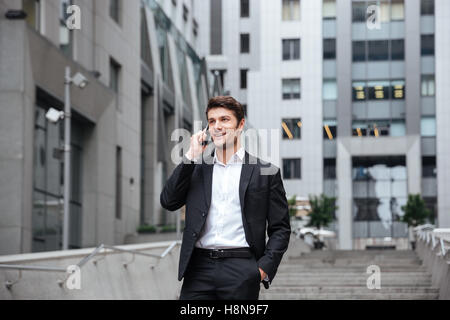 Fröhliche junge Unternehmer in der Stadt spazieren und reden über Handy Stockfoto