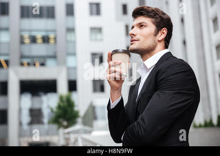 Nachdenklicher junger Geschäftsmann, trinken Kaffee und wegnehmen denken in der Nähe von Business-center Stockfoto