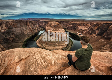 Horseshoe Bend, Colorado River und ein Wanderer am Rand sitzen und genießen Sie den Panoramablick. Stockfoto