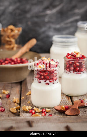 Frischen Joghurt mit Granatapfelkernen und Nussbaum in einem Glas Gläser zum Frühstück Stockfoto