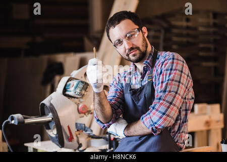 Master vertreibt seine eigenen Produkte. Männliche Schreiner haben eine Idee im Workshop Stift in der Hand halten Stockfoto