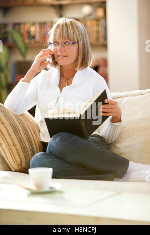 Junge Frau liest auf sofa Stockfoto