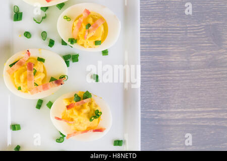 Deviled Eiern garniert mit grünen Zwiebeln und Speck. Stockfoto