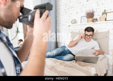 Glücklicher Mann nehmen Foto von seinem Freund im Schlafzimmer Stockfoto