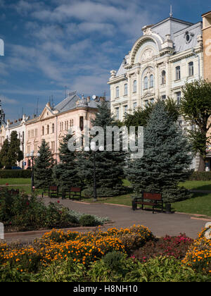 Schöne Gebäude in der Umgebung Teatralina Square in Czernowitz, Ukraine. Hübsche Blumen blühen im Vordergrund. Stockfoto