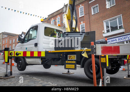 "Hubarbeitsbühnen" stützt sich auf alle seine vier Hydraulik-Wagenheber, während ein Arbeiter Weihnachtsbeleuchtung in Guildford installiert Stockfoto