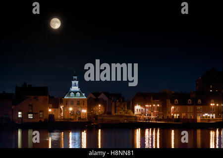 Supermoon steigt über dem Hafen von Kings Lynn in Norfolk UK im November 2016. Gebäude, Nachtlichter und Wasserreflexion leuchten die Stockfoto