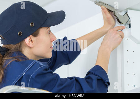 junge weibliche Elektriker Installation Steckdose auf Wand mit Schraubendreher Stockfoto