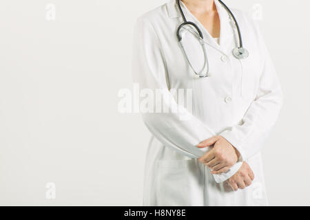 Weibliche Allgemeinmedizin mit Stethoskop posiert in weißen medizinische Uniform zuversichtlich Stockfoto