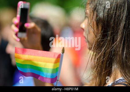 NEW YORK CITY - 21. Juni 2016: Eine junge Frau nimmt ein Foto während winken einen Regenbogen Flagge zur Unterstützung der jährlichen Gay-Pride-Parade Stockfoto