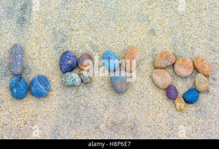 das Wort "Liebe" dargelegt in Steinen auf dem Sand liegen. Stockfoto