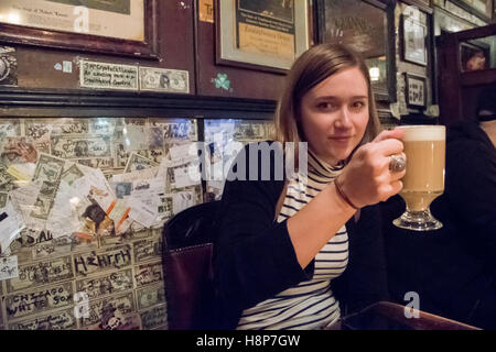 Dublin, Irland - junge Frau hält einen Drink in einem Pub in der Stadt Dublin, die Hauptstadt der Republik Irland. Stockfoto