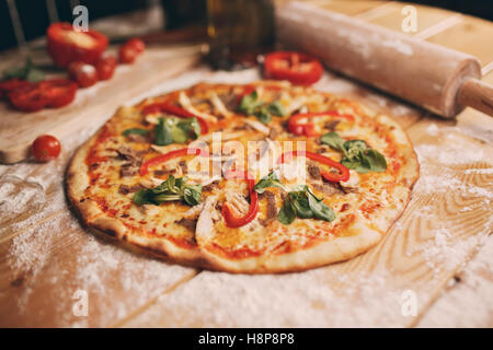 Top Wiev Pizza liegt auf strukturelle Woden Tisch in der Nähe ein Holzbrett, die es alle Zutaten gibt gehackt. Stockfoto