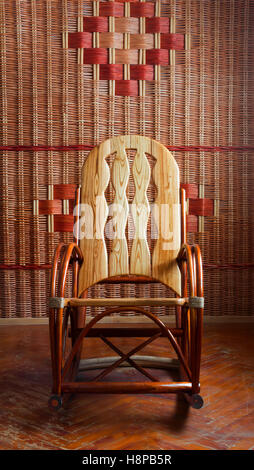 Schaukelstuhl Holz an der Wand Hintergrund Wicker, Vorderansicht Stockfoto